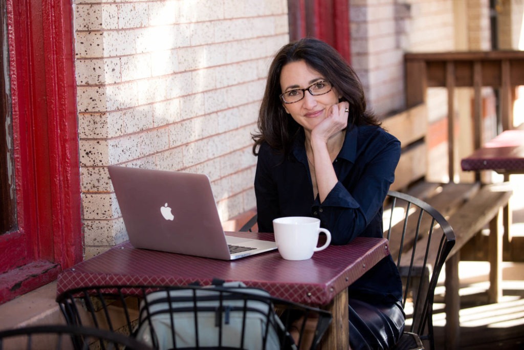 headshot of a women working on her computer at a cafe