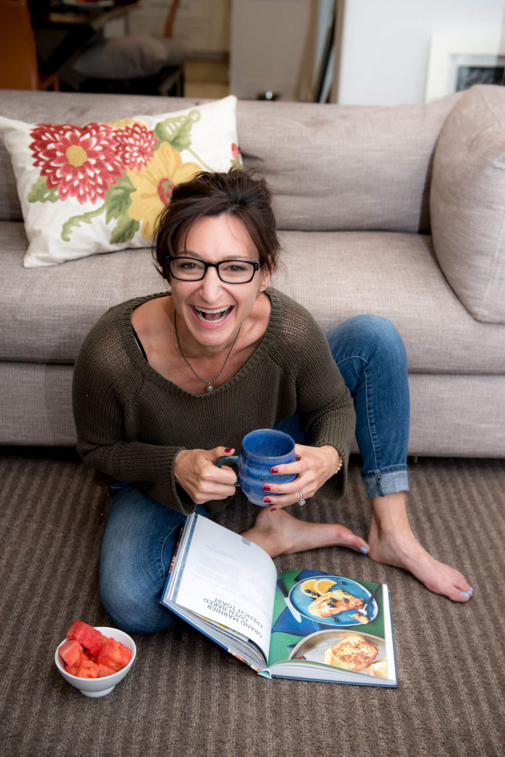 lifestyle headshot of a women in her living room laughing and drinking coffee
