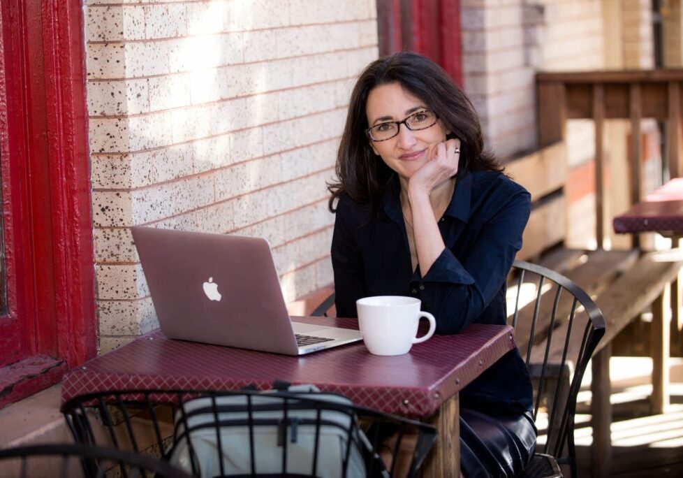 headshot of a women working on her computer at a cafe